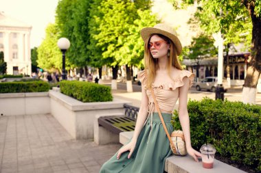 Güzel bir kadın parkta bir içkiyle yürüyor. Hayat tarzı.