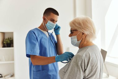 Steteskoplu sağlık hizmetleri maskeli bir doktor.