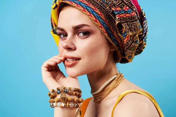 Vacker kvinna i flerfärgad turban attraktiv utseende smycken leende blå bakgrund — Stockfoto