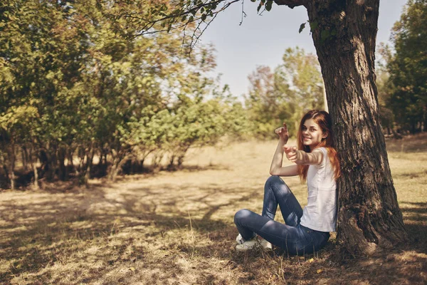 Симпатичная женщина, сидящая у дерева. — стоковое фото