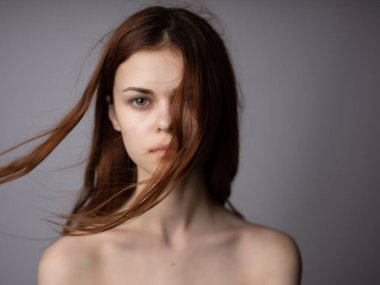 Kadın saçı, çıplak omuzlar, açık ten rengi, koyu renk arka plan.