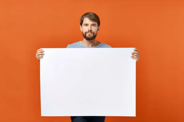 Funny man holding a mockup poster discount orange background — Stock Photo, Image