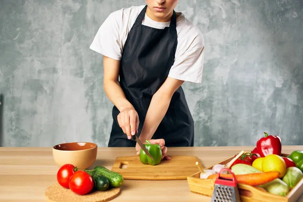 Cook woman on the kitchen cutting vegetables cutting board