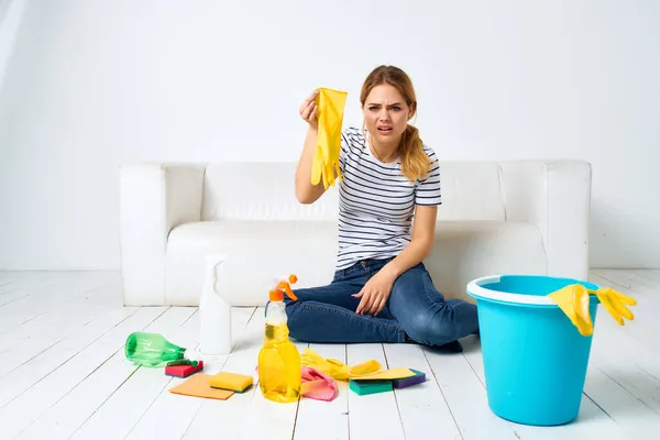 Kanepenin yanındaki temizlikçi kadın. Apartmanın arka planını temizliyor. — Stok fotoğraf