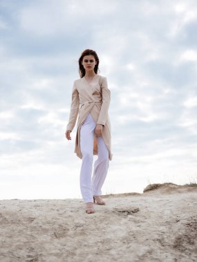 Kum modelinde kayaların yanında poz veren kadın Seyahat et