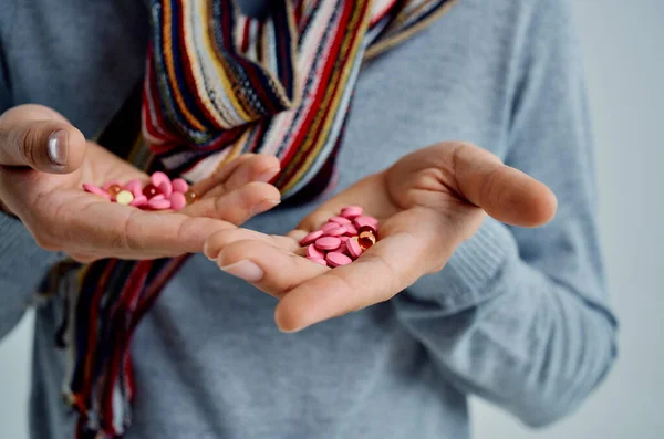 Hombre enfermo en un suéter con pastillas en la mano problemas de salud fondo de luz — Foto de Stock