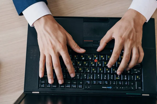 Чоловік друкує на клавіатурі ноутбука зверху — стокове фото