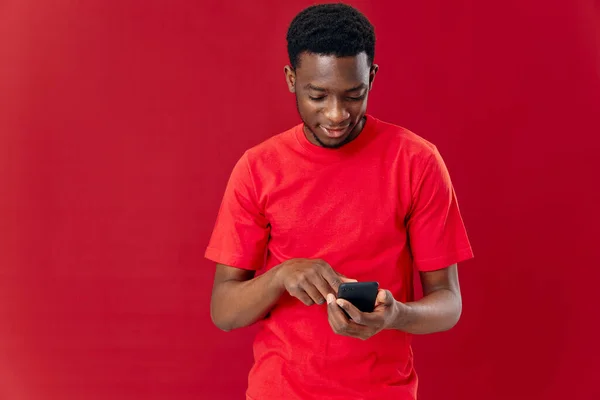 Kırmızı tişörtlü bir adam elinde telefonla duygularıyla iletişim kuruyor. — Stok fotoğraf