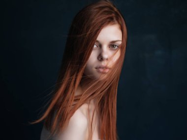 Çıplak omuzlu, kızıl saçlı bir kadın.