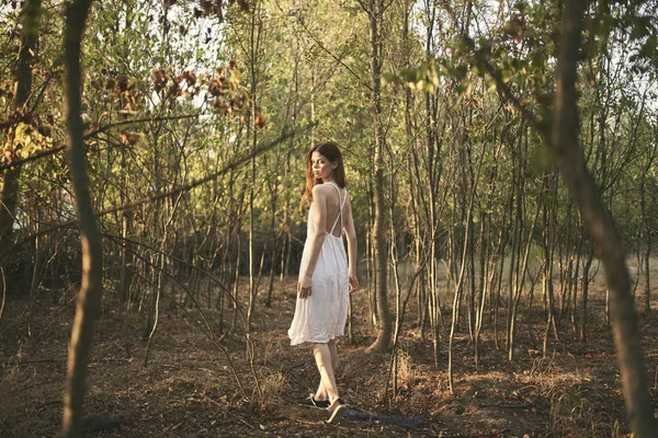Beyaz elbiseli güzel bir kadın ormanda yürüyor. — Stok fotoğraf