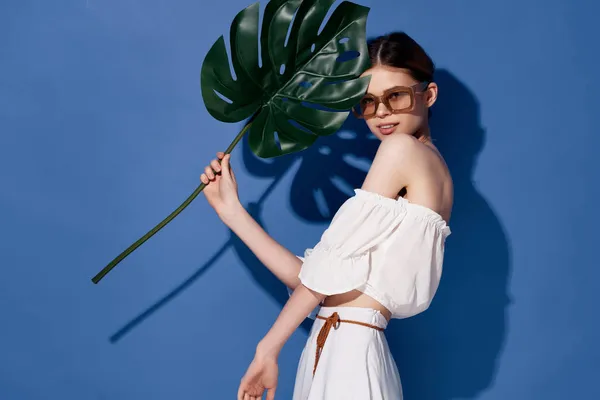 Vacker kvinna som håller palmblad i händerna Exotiskt mode blå bakgrund — Stockfoto