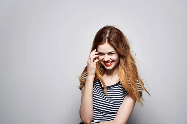 Belle femme dans un geste de t-shirt rayé avec ses mains fond clair — Photo