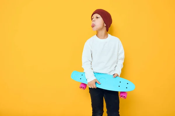 陽気な小さな子供でA赤い帽子スケートボードで彼の手スタジオポーズ — ストック写真