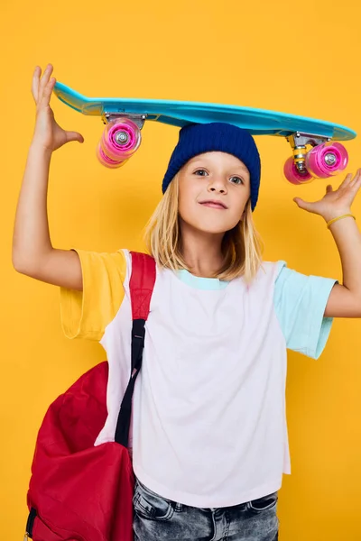Foto von niedlichen kleinen Mädchen glücklich nettes Kind mit Skateboard-Kind mit Rucksack gelben Hintergrund — Stockfoto