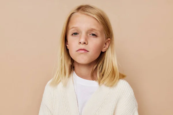 Позитивная маленькая девочка в белом свитере на бежевом фоне — стоковое фото