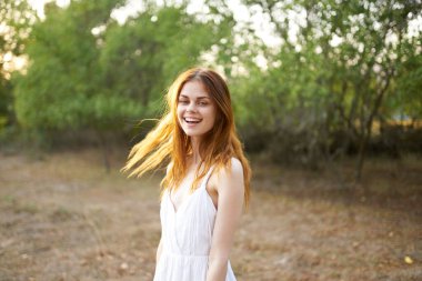 Sahada beyaz elbiseli neşeli bir kadın.