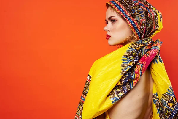 Vacker kvinna i flerfärgad turban attraktiv utseende smycken röd bakgrund — Stockfoto