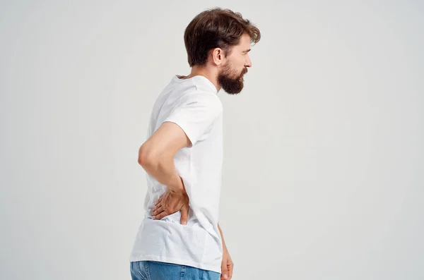Эмоциональный мужчина в белой футболке лекарство от стресса спины студийное лечение — стоковое фото