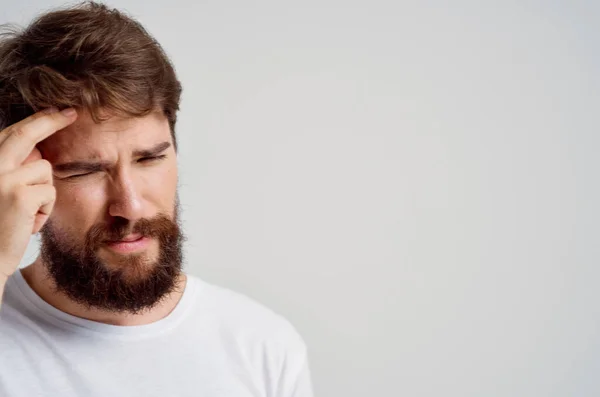 Emotionele man in een wit t-shirt hoofdpijn migraine problemen Studio behandeling — Stockfoto