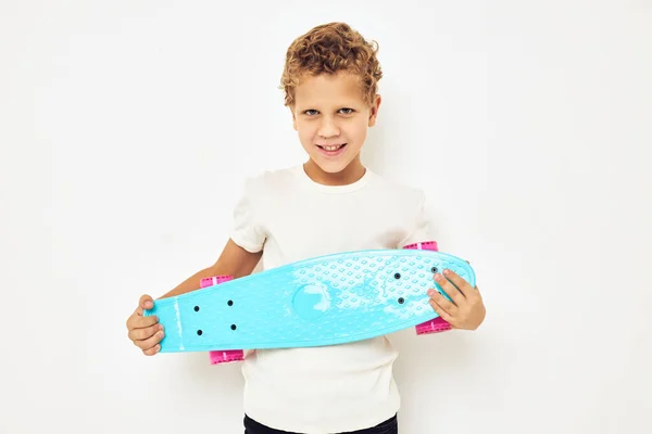 Schattig stijlvol jongen krullend haar met skateboard lichte achtergrond — Stockfoto