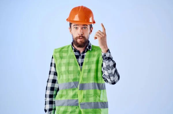 Working man groen vest oranje helm workflow hand gebaren blauwe achtergrond — Stockfoto