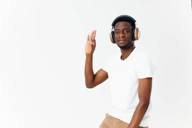 Beyaz tişörtlü Afro-Amerikalı müzik dinliyor. El hareketi hafif arka plan.
