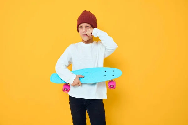 陽気な小さな子供でA赤い帽子スケートボードで彼の手黄色の背景 — ストック写真