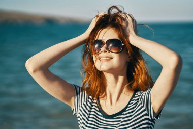 Güneş gözlüğü takan neşeli kadın yaz yürüyüşüne çıkıyor.