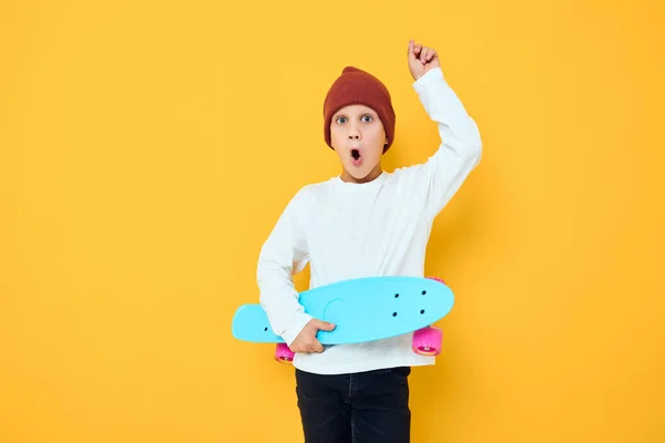 白いセーターでクールな笑顔の男の子スケートボードエンターテイメント黄色の背景 — ストック写真
