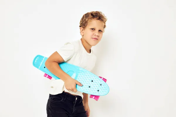 Portrait of young smiling kid curly hair with skateboard light background — Stock Photo, Image