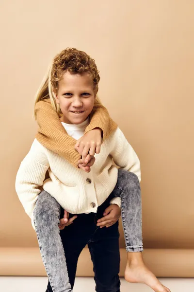 Fiú és lány szórakoztató divat fiatal gyermekkor bézs háttér — Stock Fotó