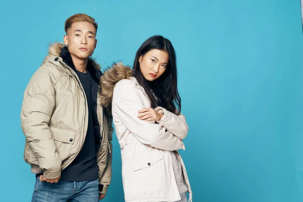 Молода пара азіатської зовнішності в зимових куртках позує синій фон — стокове фото