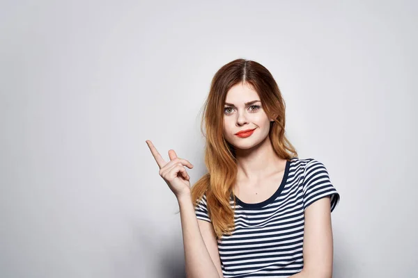 Femme gaie dans un geste de t-shirt rayé avec ses mains studio mannequin — Photo
