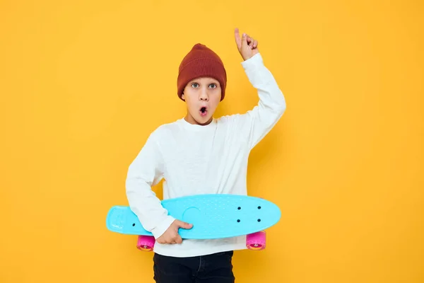 Portré aranyos fiúk egy fehér pulóver gördeszka szórakozás elszigetelt háttér — Stock Fotó