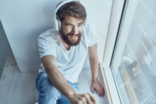 Man in wit t-shirt zit in de kamer met hoofdtelefoon rust — Stockfoto