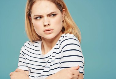 Yüzünde çizgili tişört teneke tabağı ve elleri mavi arka planı olan kızgın bir kadın.