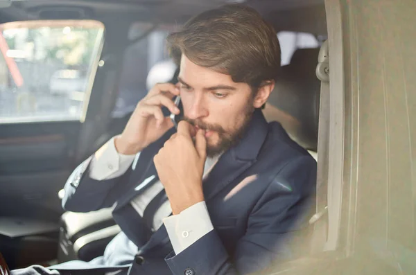 Homem barbudo em um terno em um carro uma viagem ao trabalho comunicação por telefone — Fotografia de Stock