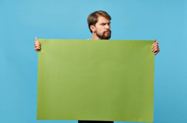 Neşeli yeşil afiş elinde boş bir sayfa mavi arka planda