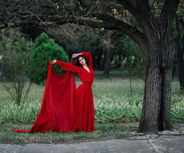 Woman in red dress in forest charm luxury tree. High quality photo