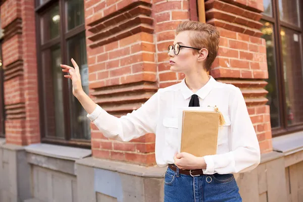 Student s brýlemi procházky po městě s knihou vzdělávání — Stock fotografie