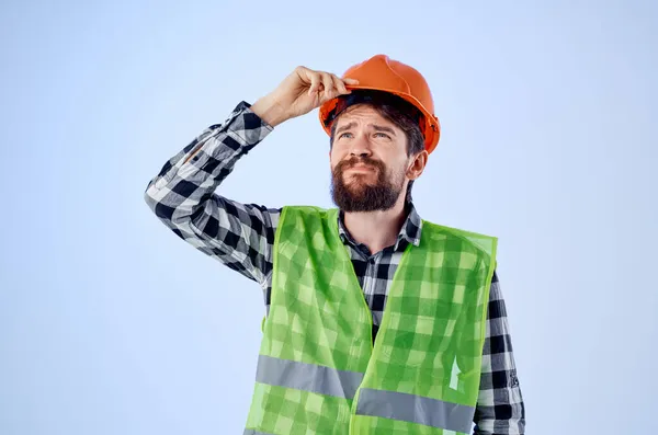 Рабочий человек зеленый жилет оранжевый шлем рабочего процесса руку жесты синий фон — стоковое фото