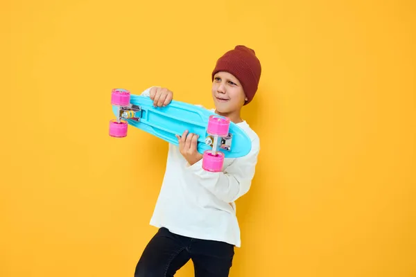 赤い帽子のスケートボードのかわいい男の子の肖像画彼の手スタジオポージング — ストック写真