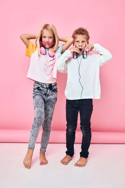 Niños con ropa elegante posando auriculares de longitud completa —  Fotos de Stock