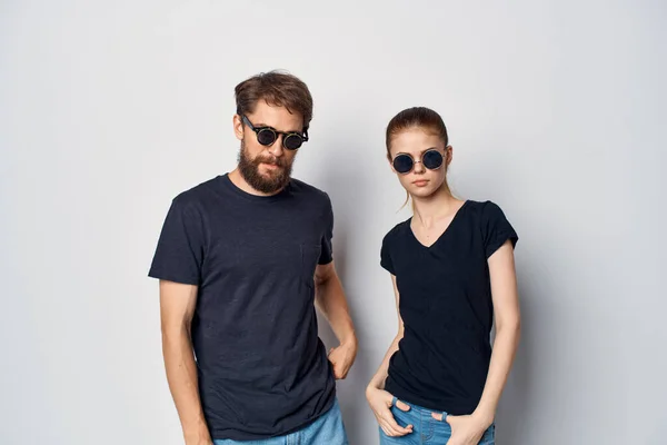 ファッショナブルな男と女で黒tシャツサングラスポーズスタジオライフスタイル — ストック写真