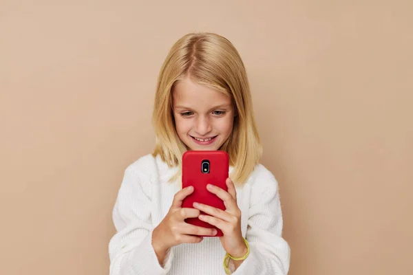 Pequeña niña positiva teléfono rojo en la mano sobre un fondo beige —  Fotos de Stock