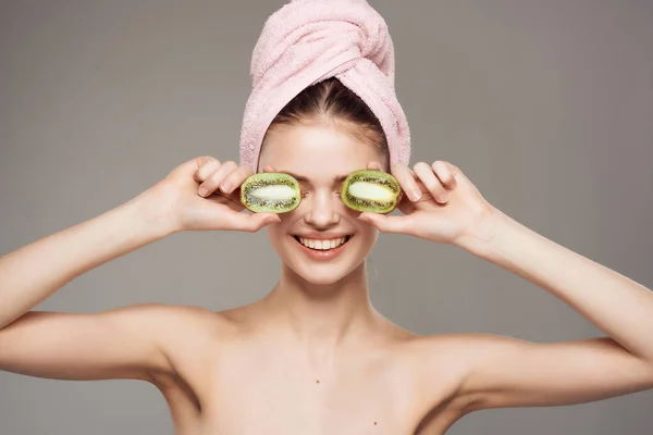 Wanita dengan handuk di kepalanya bersih kulit kiwi di tangan dipotong pandangan — Stok Foto