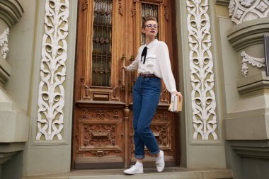 Gözlüklü güzel bir kadın kitap iletişimiyle şehirde dolaşıyor.