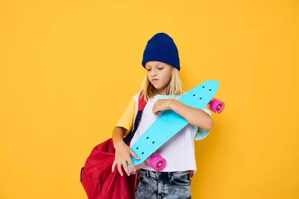 スタイリッシュな女の子幸せなかわいい子供とスケートボードの子供付きバックパック — ストック写真