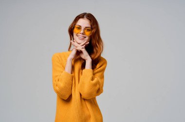 Sarı gözlüklü güzel kadın eğlenceli yaşam tarzı ışık arka planında poz veriyor.