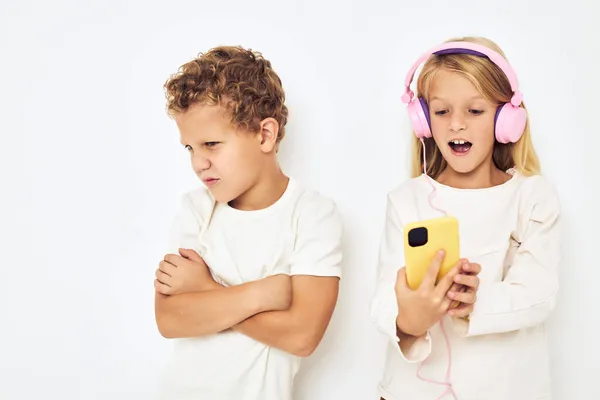 Dvě předškolní děti chlapec a dívka se žlutými růžovými sluchátky životní styl dětství — Stock fotografie